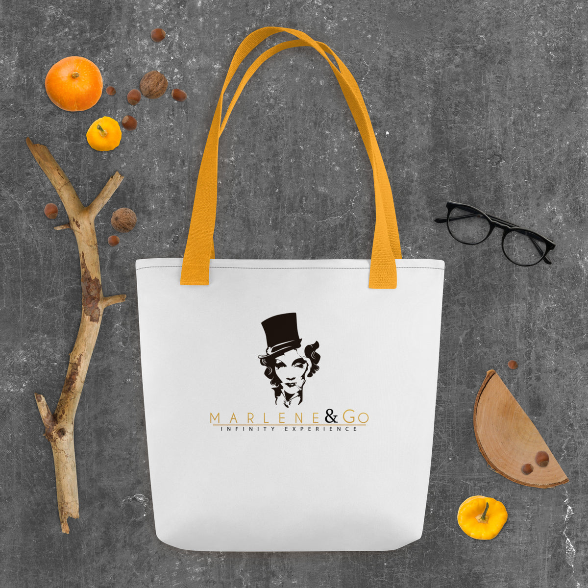 Marlene Crest Carry: bolsa blanca con emblema negro y dorado de Marlene y asas amarillas, vista frontal.